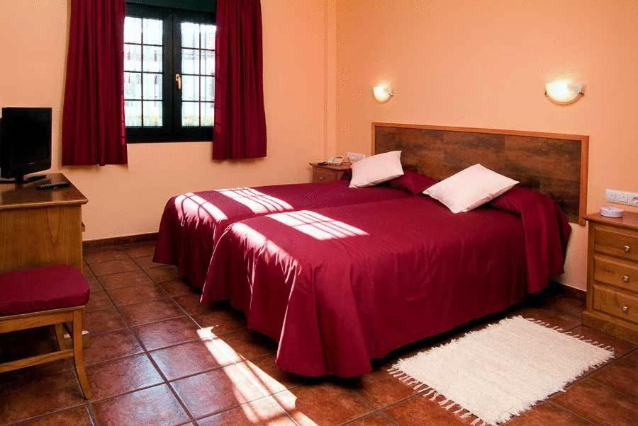 a bedroom with a large bed with a red blanket at Hotel Ruta del Poniente in Cuesta de la Palma