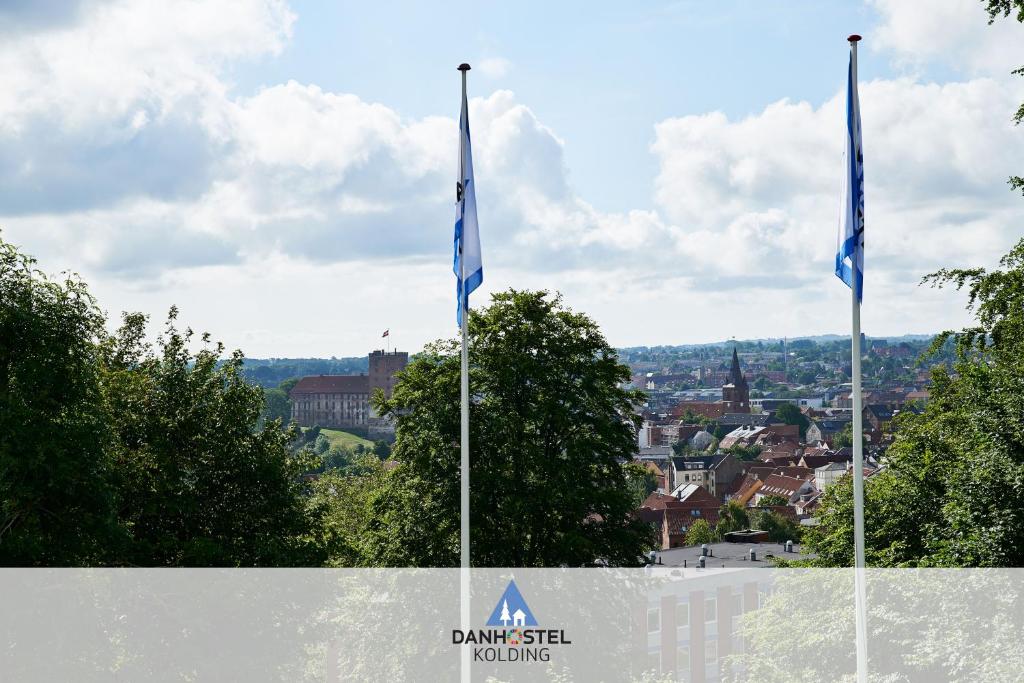 duas bandeiras estão voando em frente a uma cidade em Danhostel Kolding em Kolding