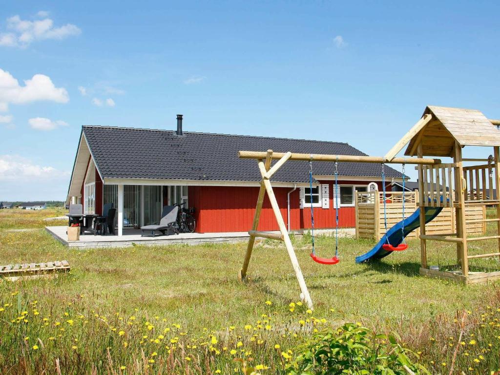 ein Haus mit einem Spielplatz davor in der Unterkunft 9 person holiday home in Brovst in Brovst