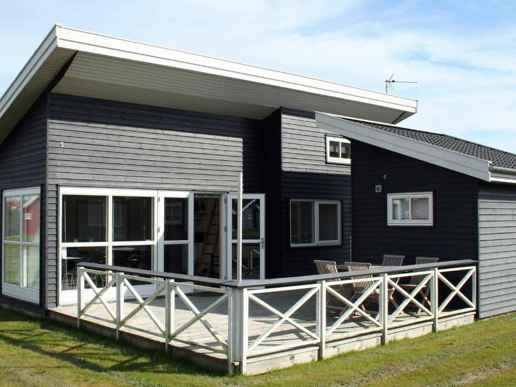a black house with a large deck in front of it at 6 person holiday home in Gudhjem in Gudhjem