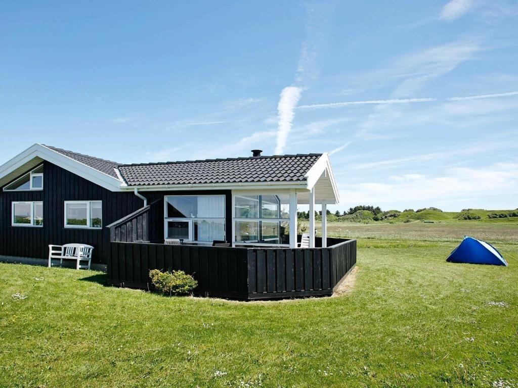 una casa negra con una gran ventana en un campo en Three-Bedroom Holiday home in Hjørring 17 en Lønstrup
