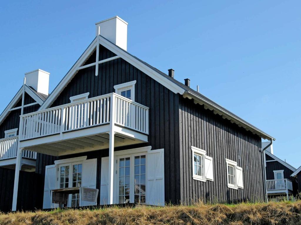 a black house with a white balcony on the side of it at 8 person holiday home in Gjern-By Traum in Gjern
