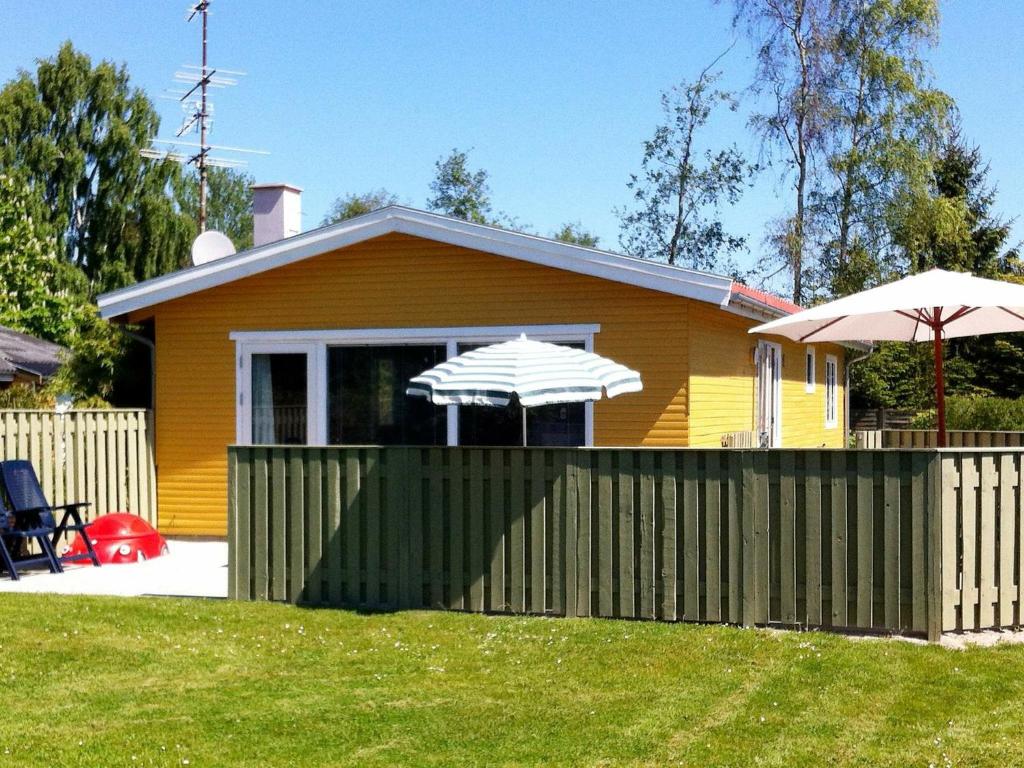 a yellow house with a fence and an umbrella at 6 person holiday home in V ggerl se in Bøtø By