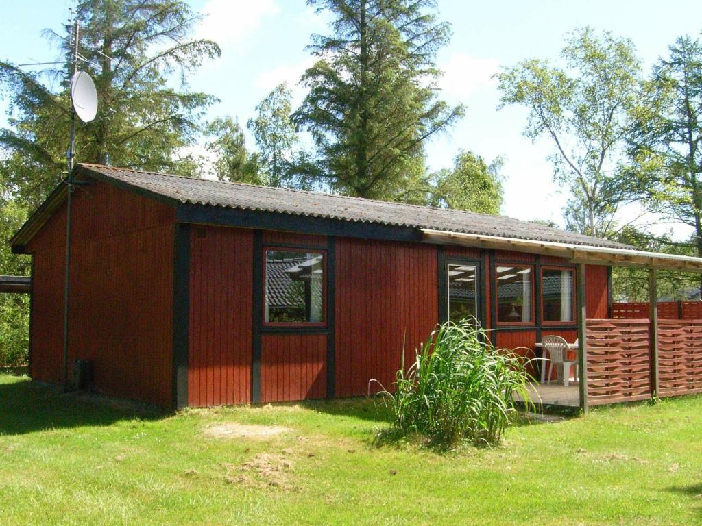 a small red house with a grassy yard at Two-Bedroom Holiday home in Væggerløse 24 in Marielyst