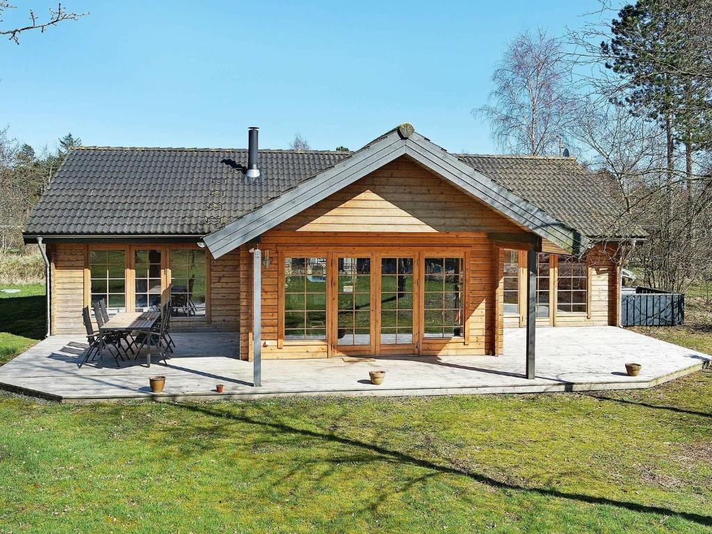 a log cabin with a large porch in a yard at Three-Bedroom Holiday home in Hadsund 28 in Odde