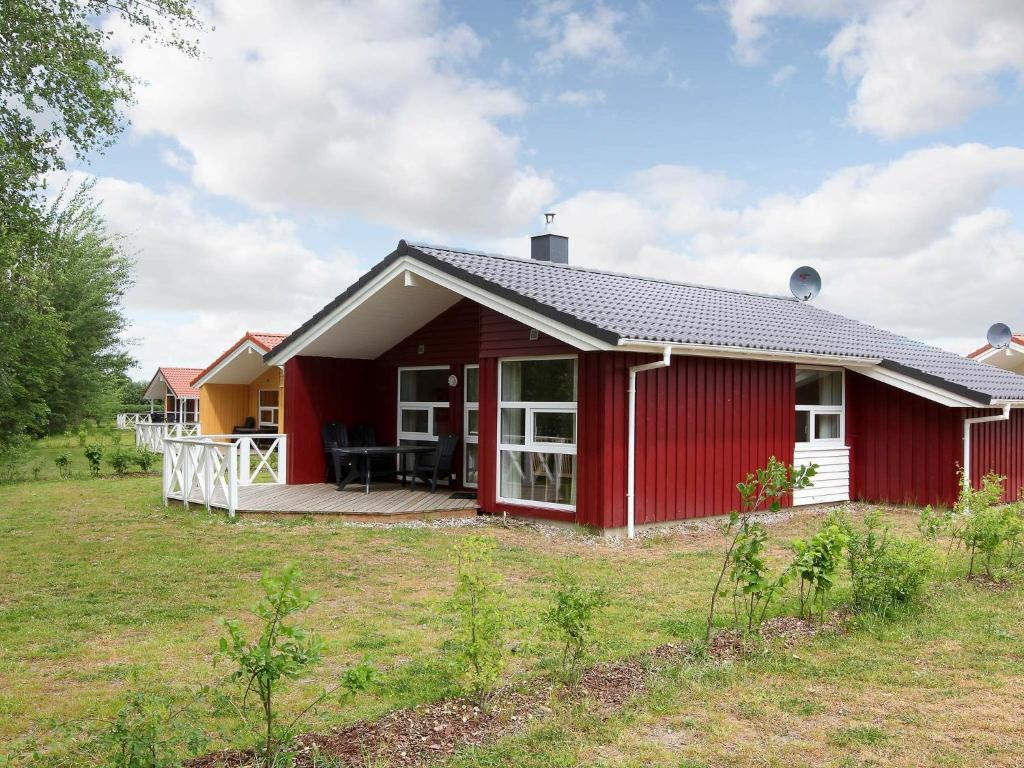 una casa roja con terraza en un patio en 6 person holiday home in GROEMITZ, en Grömitz