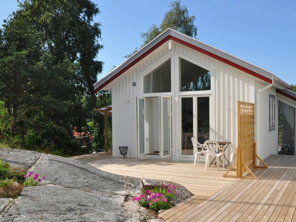 un pequeño cobertizo blanco con una mesa y sillas en una terraza en 4 person holiday home in STENUNGSUND, en Stenungsund