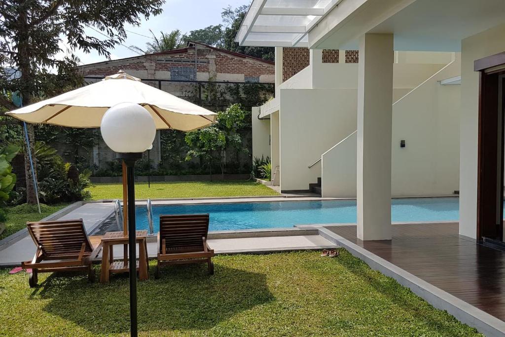 einen Tisch und Stühle mit einem Sonnenschirm neben dem Pool in der Unterkunft Bukit Dago Palace 22 in Bandung