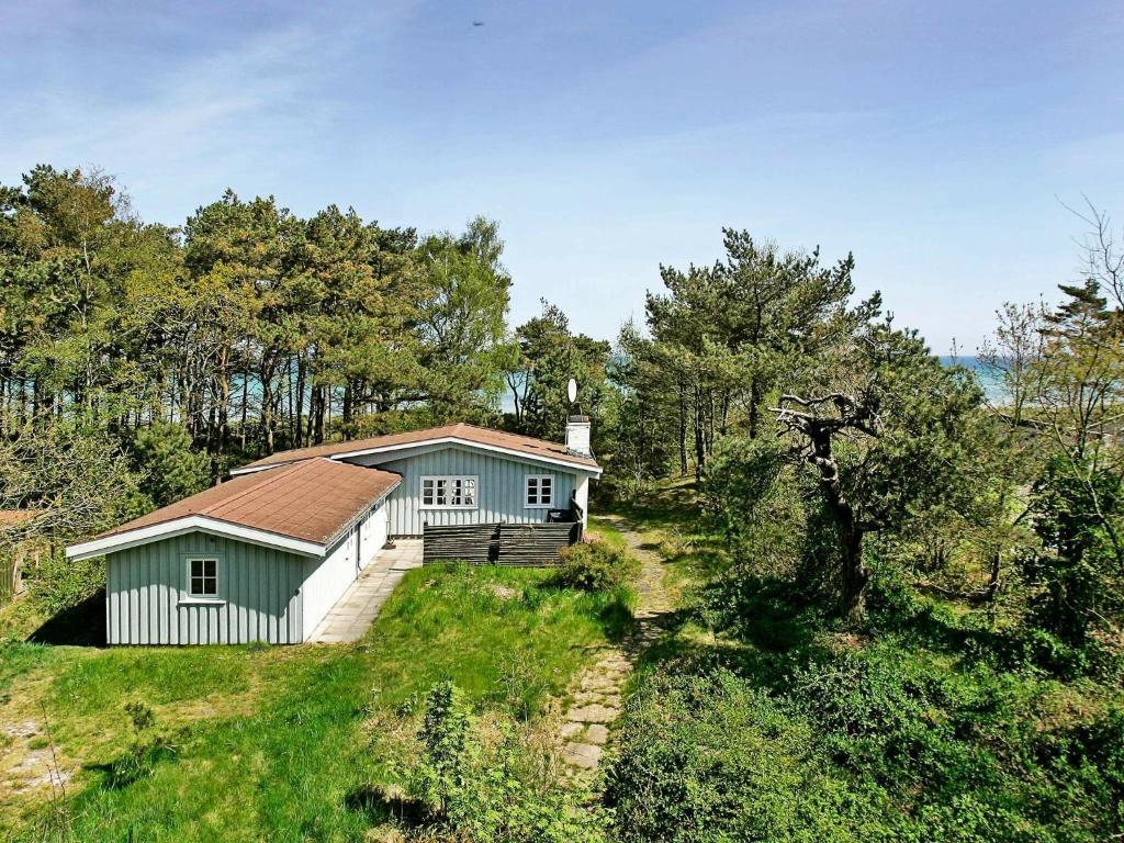 uma pequena casa no topo de uma colina com árvores em 6 person holiday home in Nex em Balke