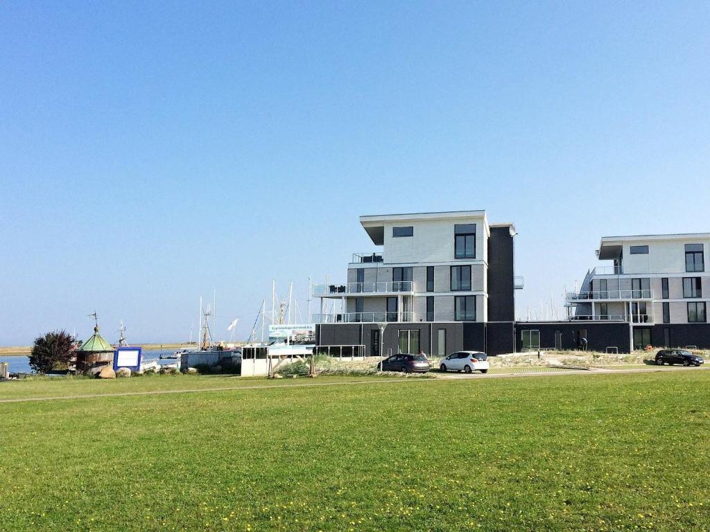 a large building with cars parked in a grass field at One-Bedroom Holiday home in Wendtorf 1 in Wendtorf