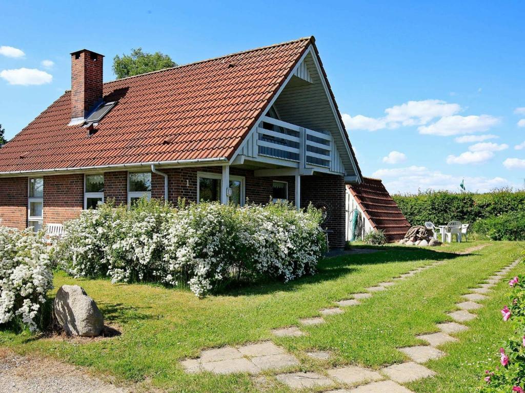 uma casa de tijolos com um telhado vermelho e alguns arbustos em 6 person holiday home in Hesselager em Hesselager