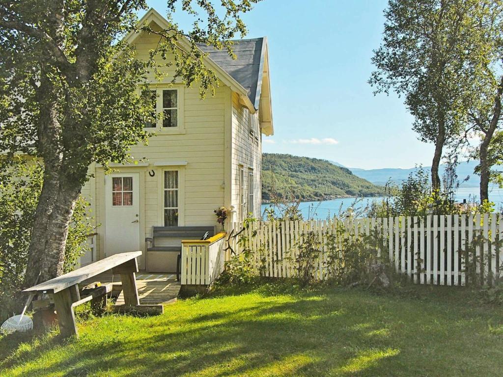 une maison blanche avec une clôture en bois et un banc dans l'établissement Three-Bedroom Holiday home in Skatvik, à Seljesletta