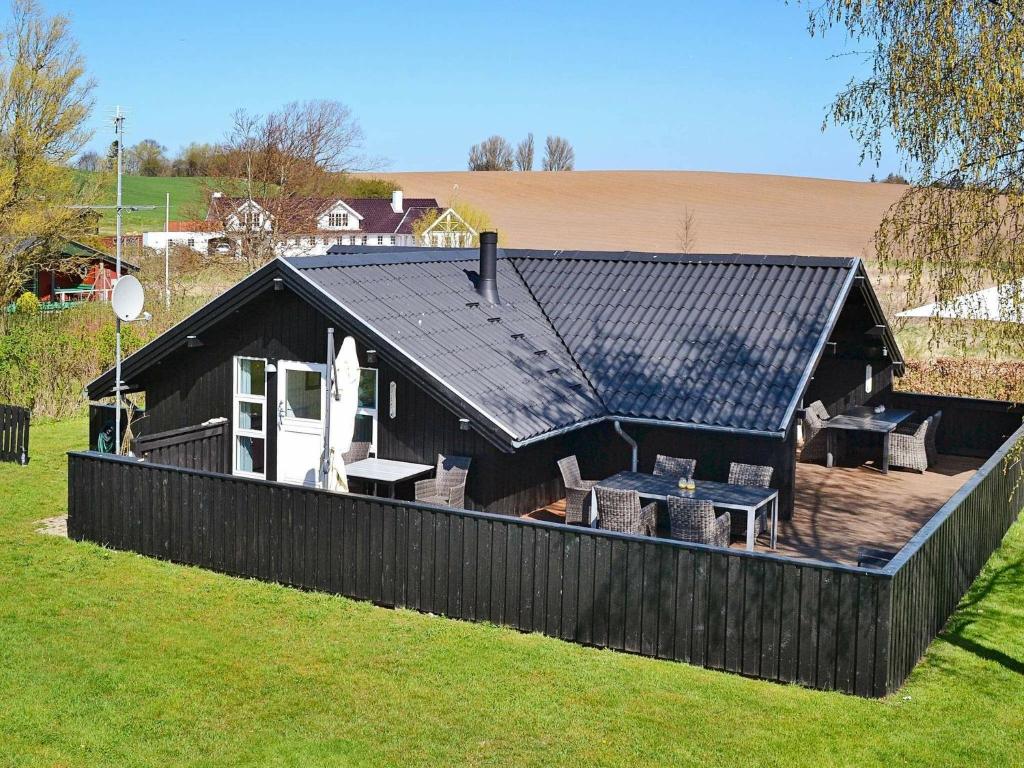 6 person holiday home in Haarby في Brunshuse: منزل بسقف أسود وسطح مع كراسي