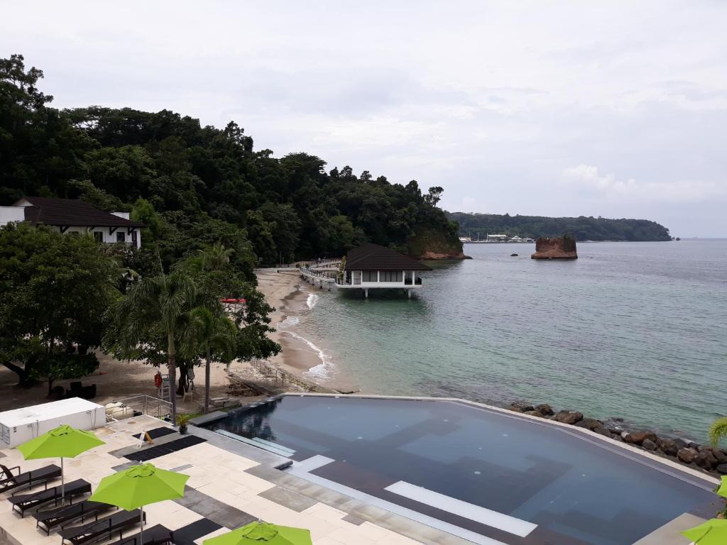 - une piscine sur une plage avec un bateau dans l'eau dans l'établissement Kamana Sanctuary Resort & Spa, à Olongapo