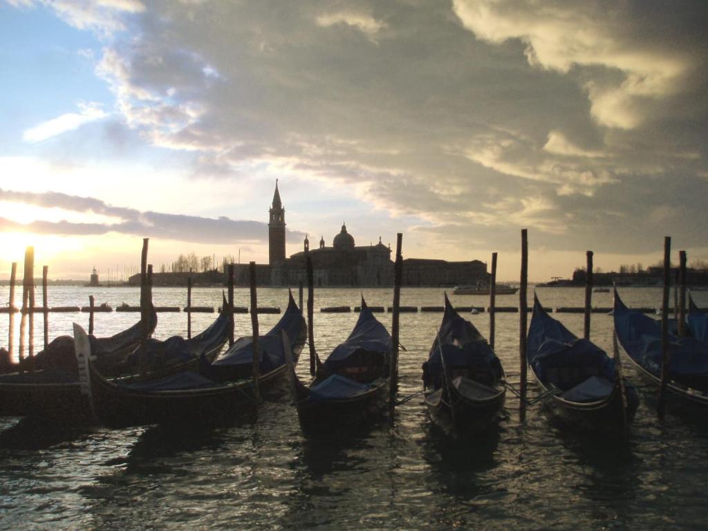 un groupe de gondoles dans l’eau avec une ville en arrière-plan dans l'établissement Rudy House Venice, à Venise