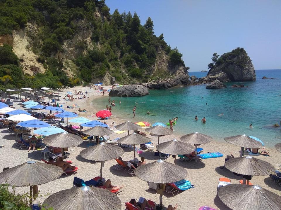 een strand met veel parasols en mensen in het water bij Achilleas Hotel in Parga