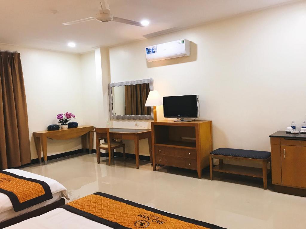 Habitación con 1 dormitorio con escritorio y TV. en Khách sạn SAO NAM en Cao Lãnh