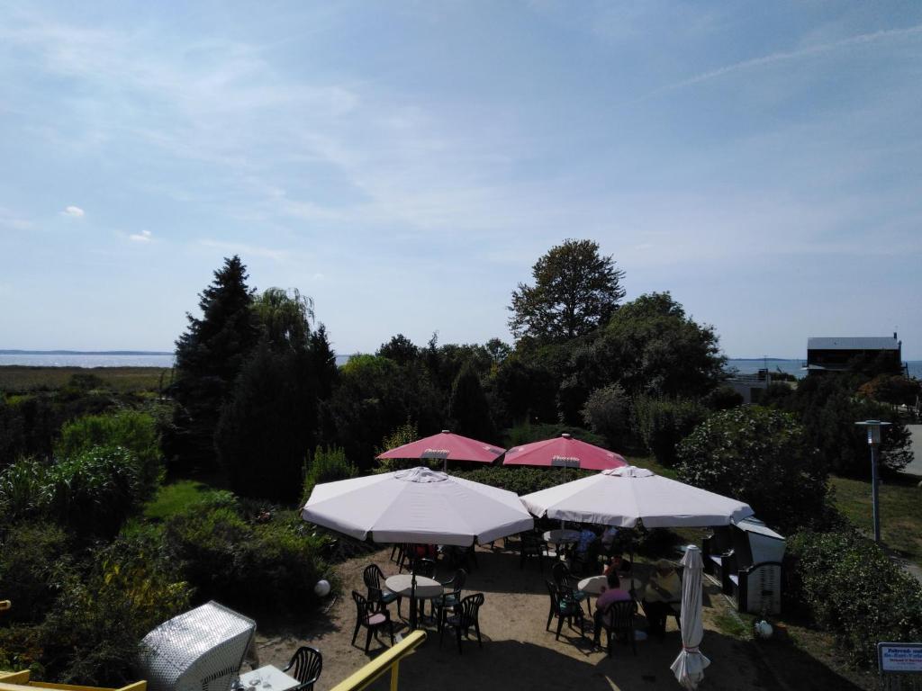 un grupo de mesas con sombrillas en un patio en Pension "Am Achterwasser" en Ueckeritz