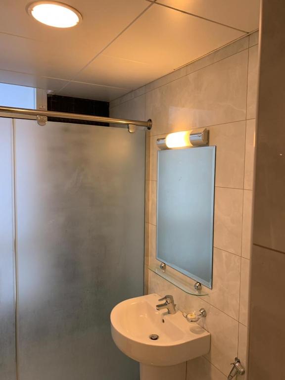 a bathroom with a sink and a shower with a mirror at Paragon Hotel Apartments in Abu Dhabi