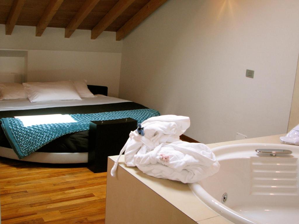 a bathroom with a bed and a bath tub next to a sink at Parizzi Suites & Restaurant in Parma