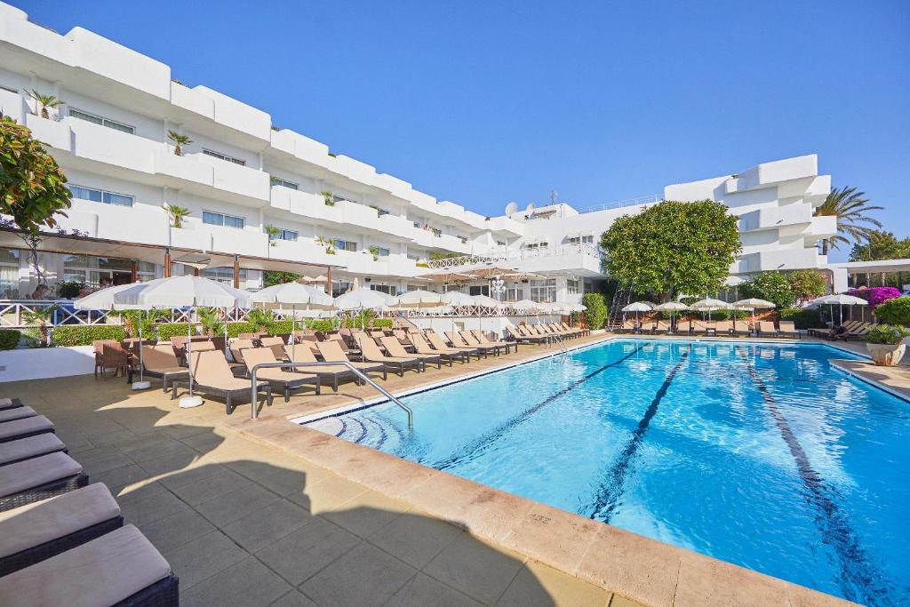 una piscina con sillas y sombrillas junto a un hotel en Hotel Rocamarina - Adults Only, en Cala d´Or