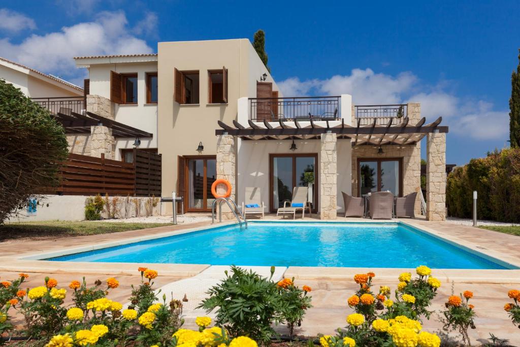 a villa with a swimming pool in front of a house at Aphrodite Hills Rentals - Junior Villas in Kouklia