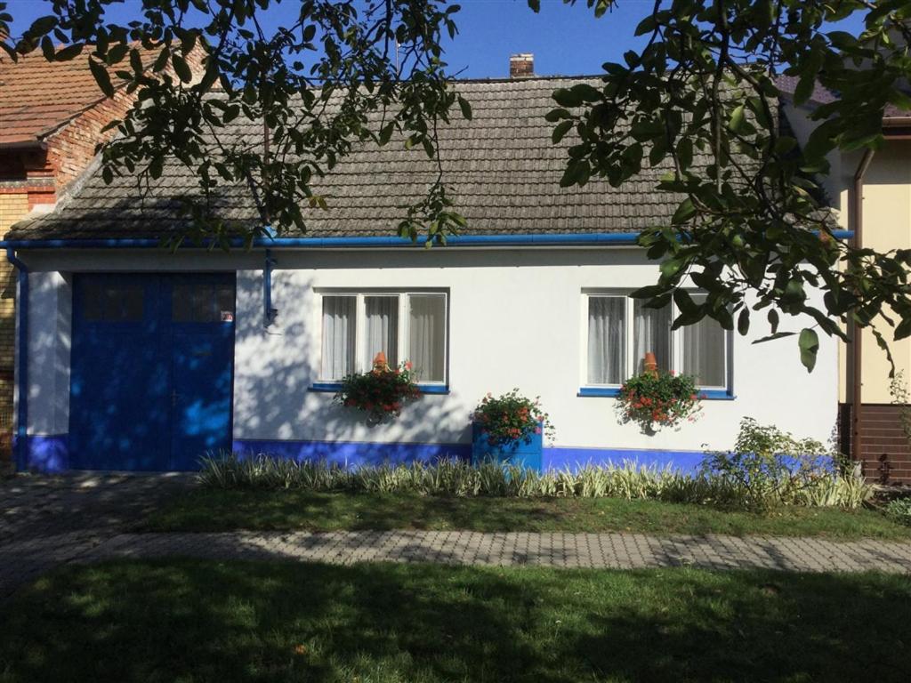une maison blanche avec des parures bleues et 2 fenêtres dans l'établissement Rekreační dům U parku, à Mikulčice