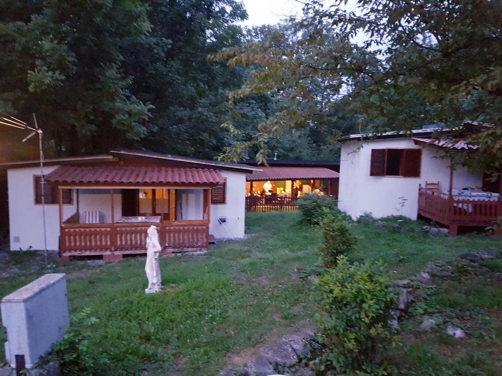 una casa bianca con portico e cortile di CROTTO CARACO APPARTAMENTI BUNGALOW CHALET a Porlezza