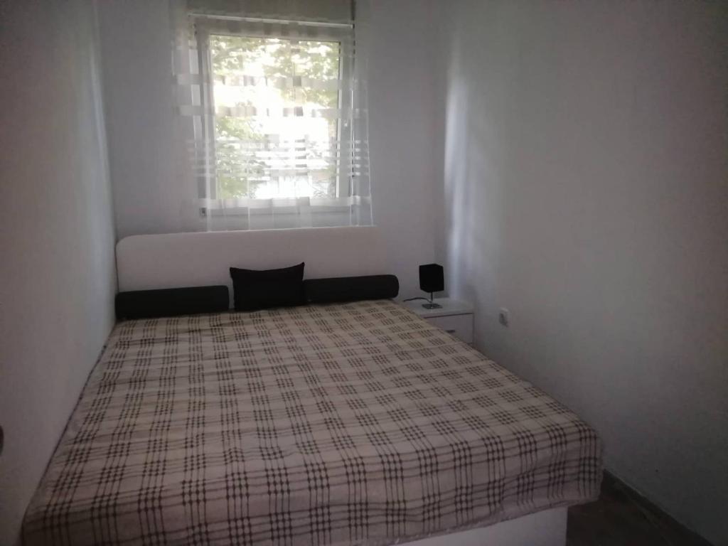 un lit dans une chambre blanche avec une fenêtre dans l'établissement Yellow apartment, central Podgorica, à Podgorica