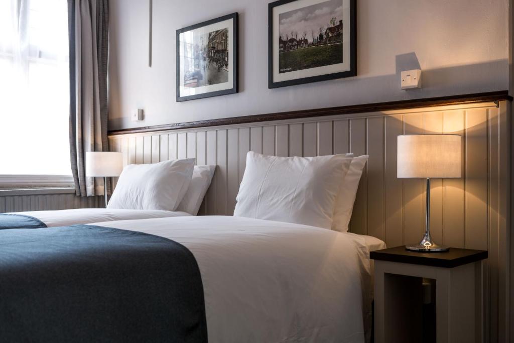 une chambre d'hôtel avec deux lits et une lampe dans l'établissement Southern Cross, à Watford
