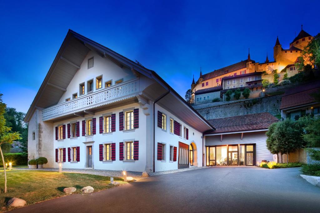 a large white building with a hill in the background at La Ferme du Château in Lucens