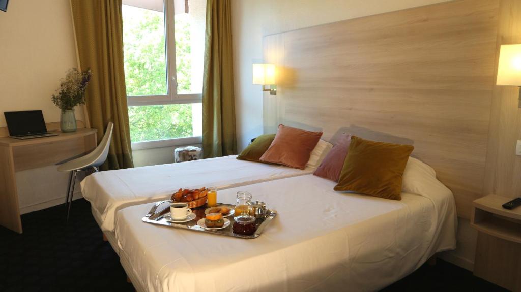 a hotel room with a tray of food on a bed at Hôtel d'Orsay in Toulouse