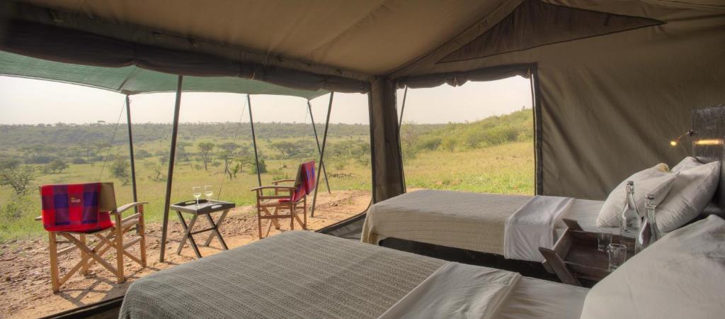 Zelt mit 2 Betten, Tisch und Stühlen in der Unterkunft Basecamp Wilderness in Naboisho
