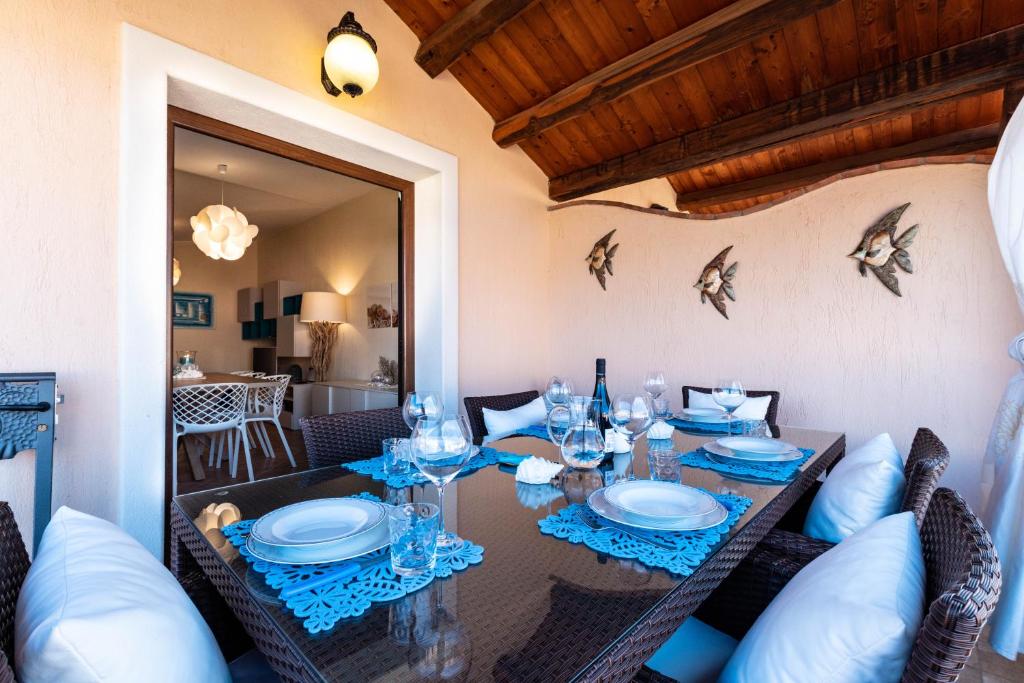 a dining room with a table with plates and glasses at La Casa delle Conchiglie in Villasimius