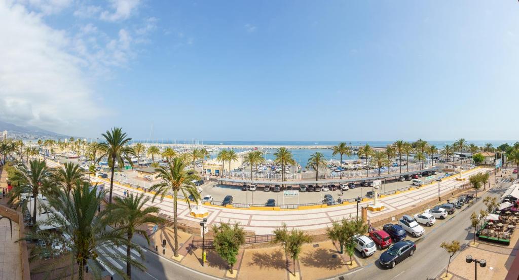 una strada cittadina con palme e l'oceano di MalagaSuite Fuengirola Beach a Fuengirola