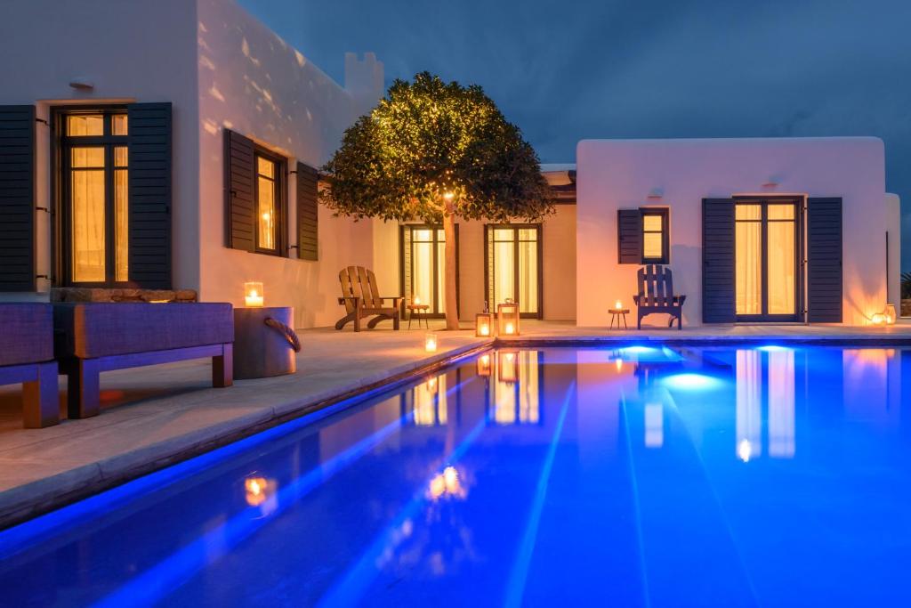 a swimming pool in front of a house at night at Myconian Platinum Senior & Deluxe Villas in Kalafatis