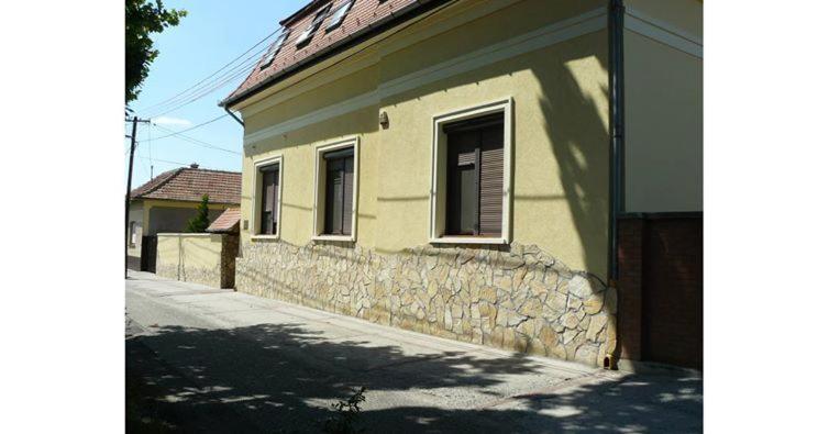 une maison avec un mur en pierre à côté d'une rue dans l'établissement Mo-Ha Panzió, à Törökszentmiklós