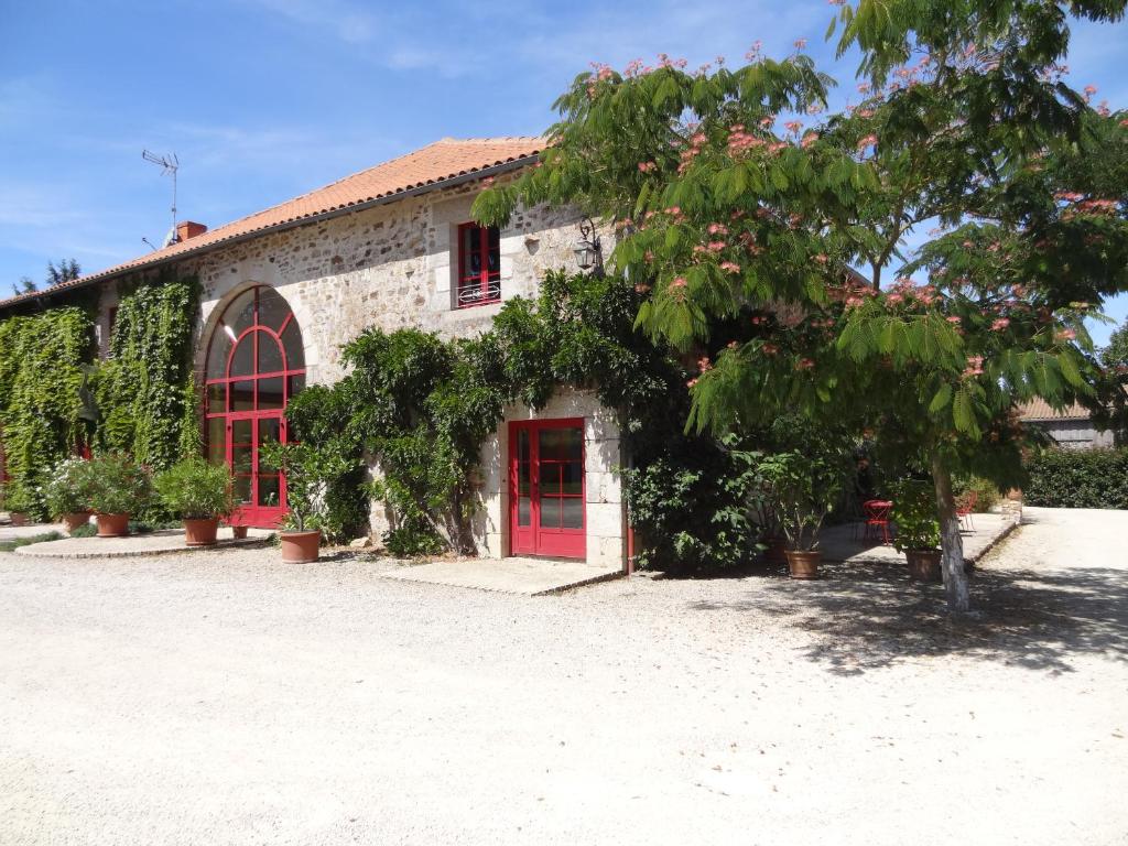 budynek z czerwonymi drzwiami i drzewem w obiekcie LA FERME DE ROUFFIGNAC w mieście Blanzac