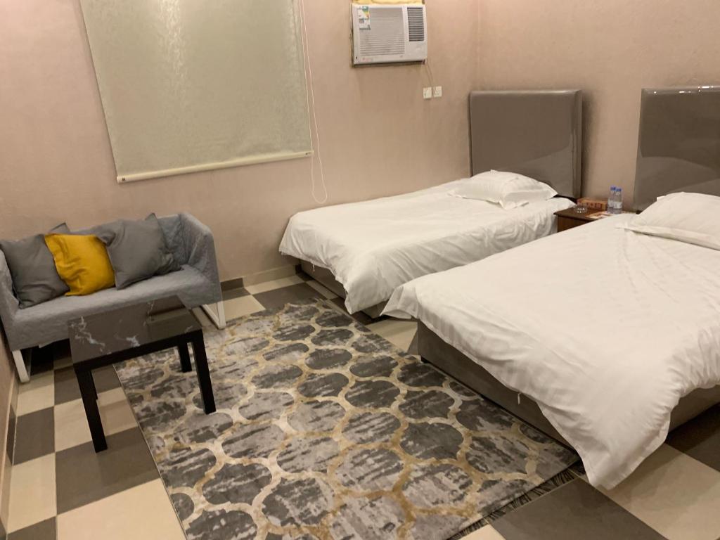 una camera con due letti e una sedia di Economic Homes Apartments a Yanbu