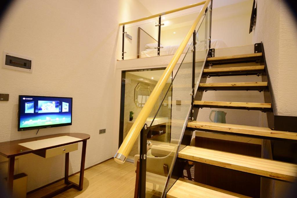 a living room with a staircase and a television at Shenzhen Mint Apartment in Shenzhen