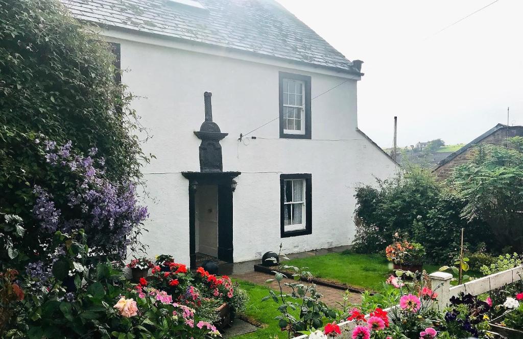 a white house with flowers in front of it at Stone House Farm in St Bees