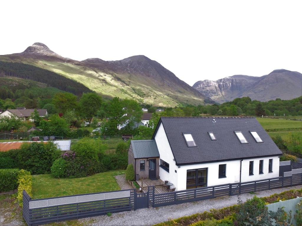 a white house with mountains in the background at Hawthorn Cottage in Glencoe