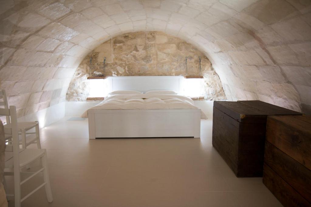 ein Schlafzimmer mit einem weißen Bett und einer Steinmauer in der Unterkunft Rifugio Ibleo in Ragusa