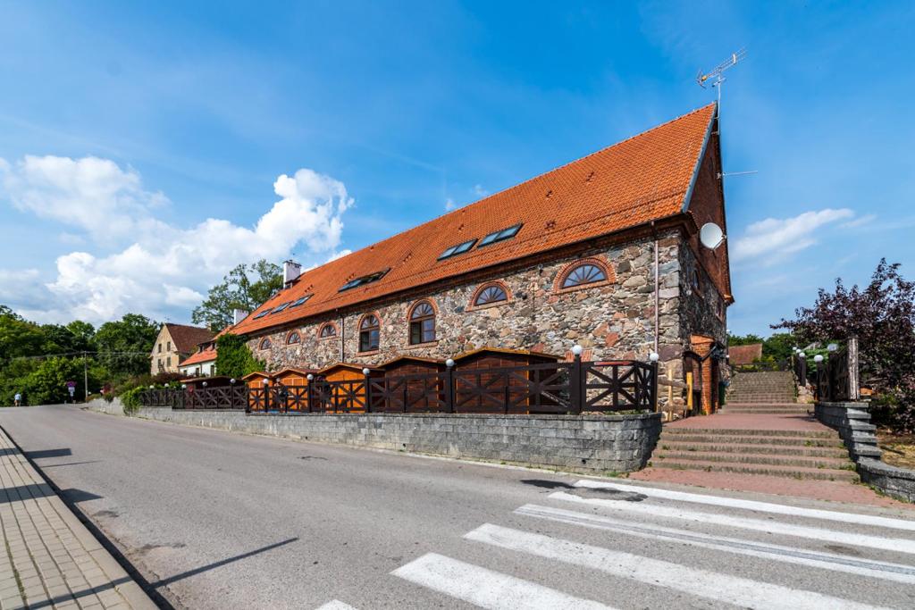 Pensjonat Sztynort في Sztynort: مبنى حجري كبير بسقف احمر على شارع