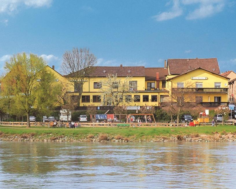 a large yellow building next to a body of water at Hotel-Restaurant Zur Mainlust in Maintal