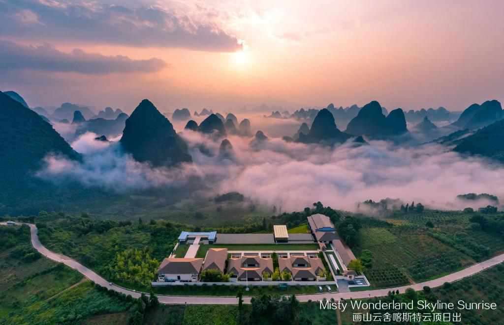 een uitzicht op een resort in de bergen met een mistige vallei bij Misty Wonderland ,Yangshuo Xingping in Yangshuo