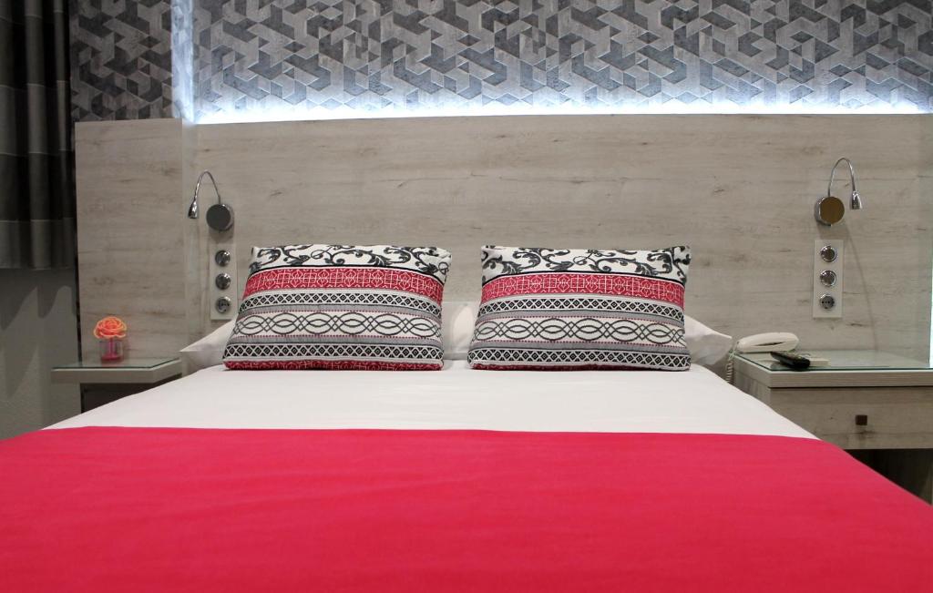 1 cama con 2 almohadas y manta roja en Hotel Restaurante Santos, en Santomera