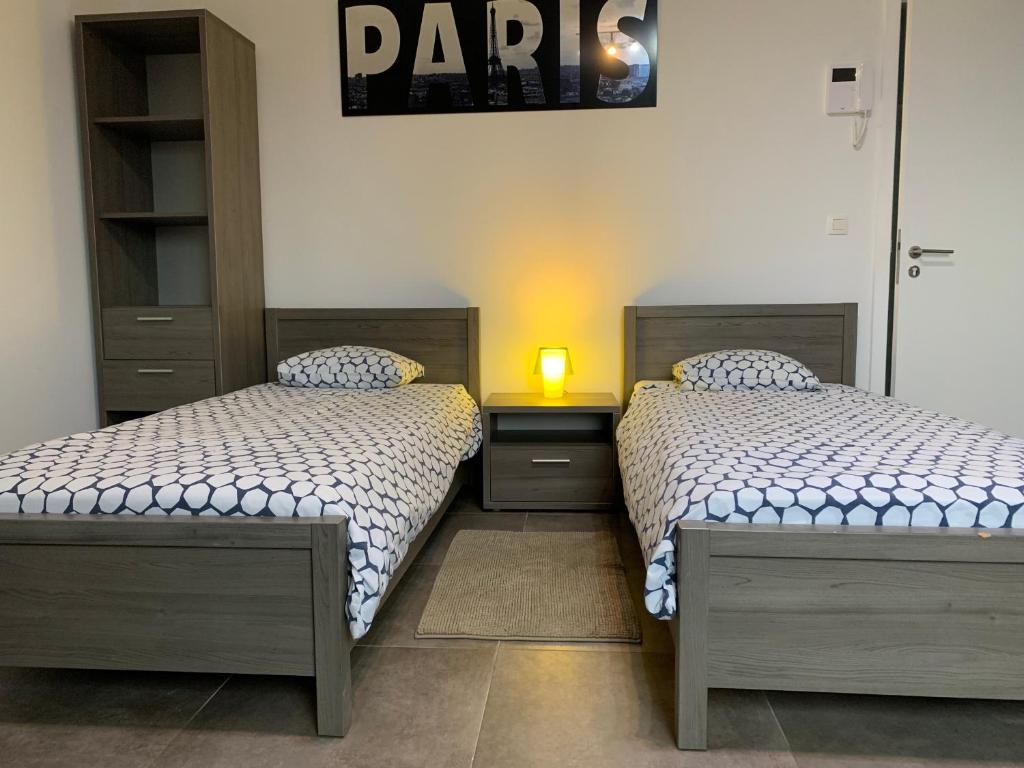 ein Schlafzimmer mit 2 Betten und einer Lampe auf einem Tisch in der Unterkunft Résidence la floraison in Brüssel