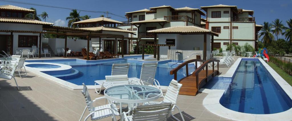 een resort met een zwembad en stoelen en een gebouw bij Apartment Terraces Porto Das Baleias in Praia do Forte