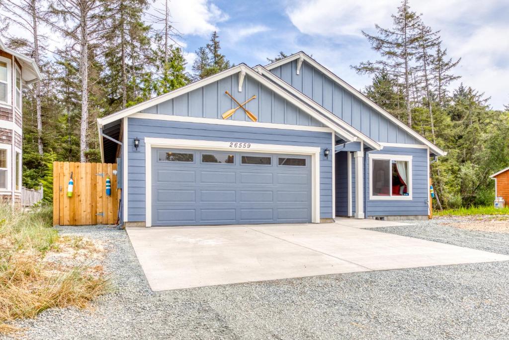 a house with a blue garage with a driveway at The Captain's Quarters in Rockaway Beach